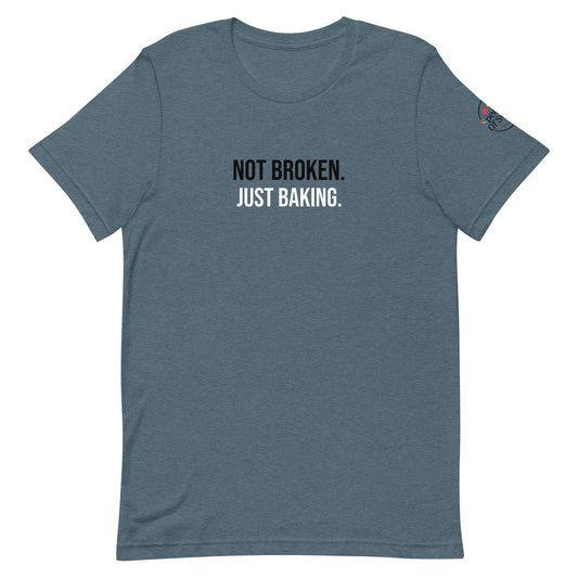 Blue t-shirt with text 'Not Broken. Just Baking.' on a white background